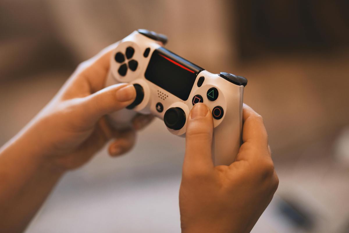 Hands holding a PlayStation controller - Australia social media ban, online gaming